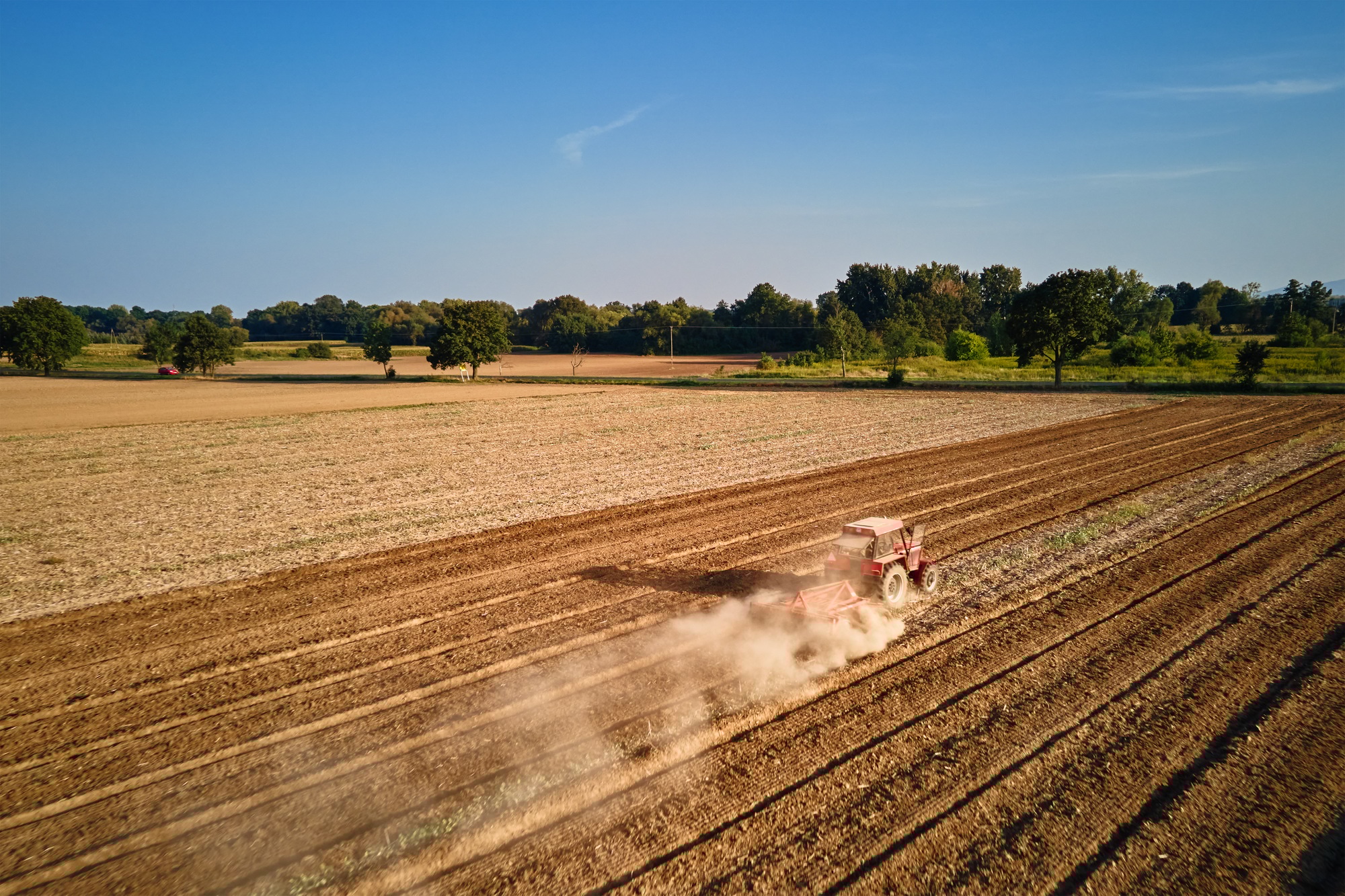 Tractor working in agricultural field, cultivating and plowing dry soil